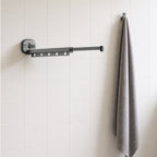 Suction Cup Drying Rack, No-Drill Telescopic Wall Rail for Laundry extended on a bathroom wall beside a hanging bath towel, for scale