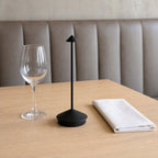 Rechargeable Touch Table Lamp, Cordless LED Desk Light for Dining, Bar & Bedside beside a wine glass on a restaurant table, showing its size