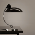 Black and chrome desk lamp on a wooden surface with a neutral background