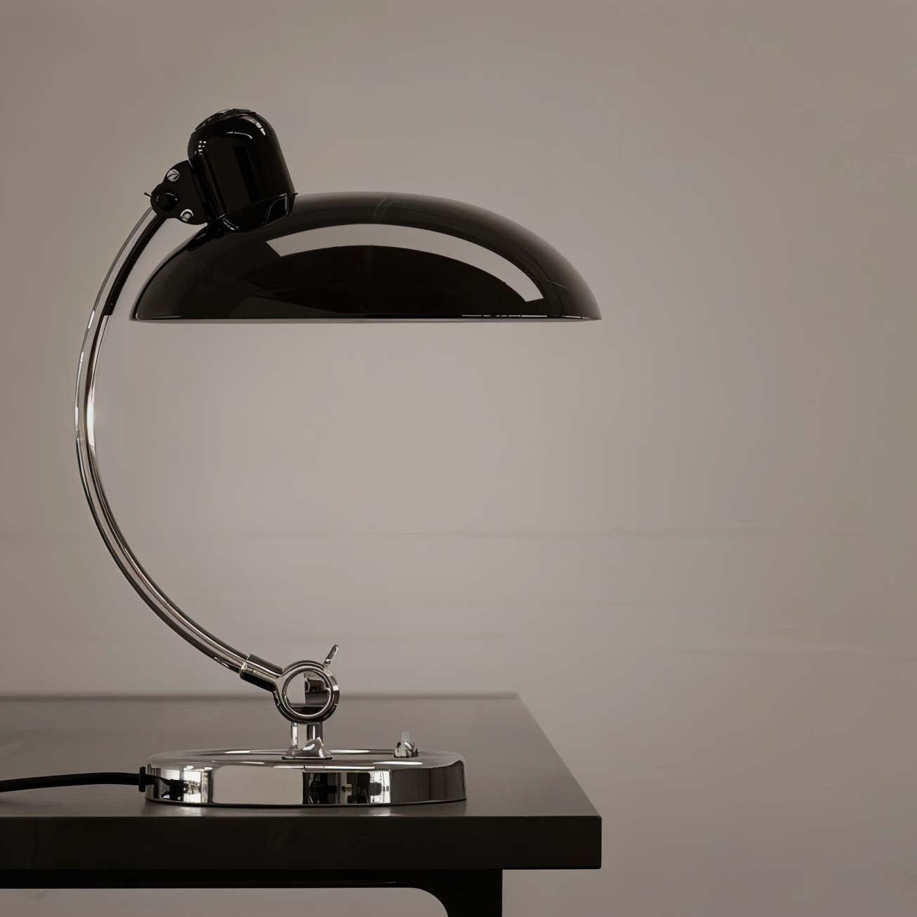 Black and chrome desk lamp on a wooden surface with a neutral background