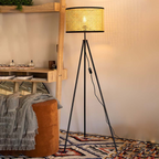 Boho standing floor lamp with handwoven wicker shade and modern tripod base studio view